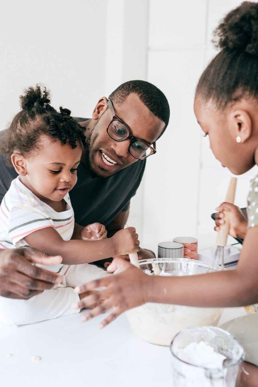Dad and young daughters baking in kitchen