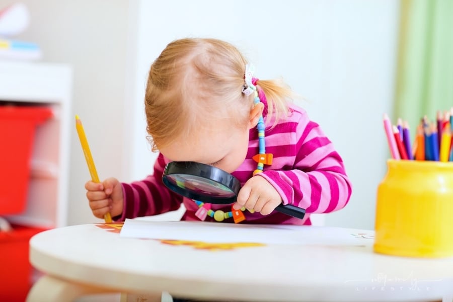 toddler girl looking through magnifying glass