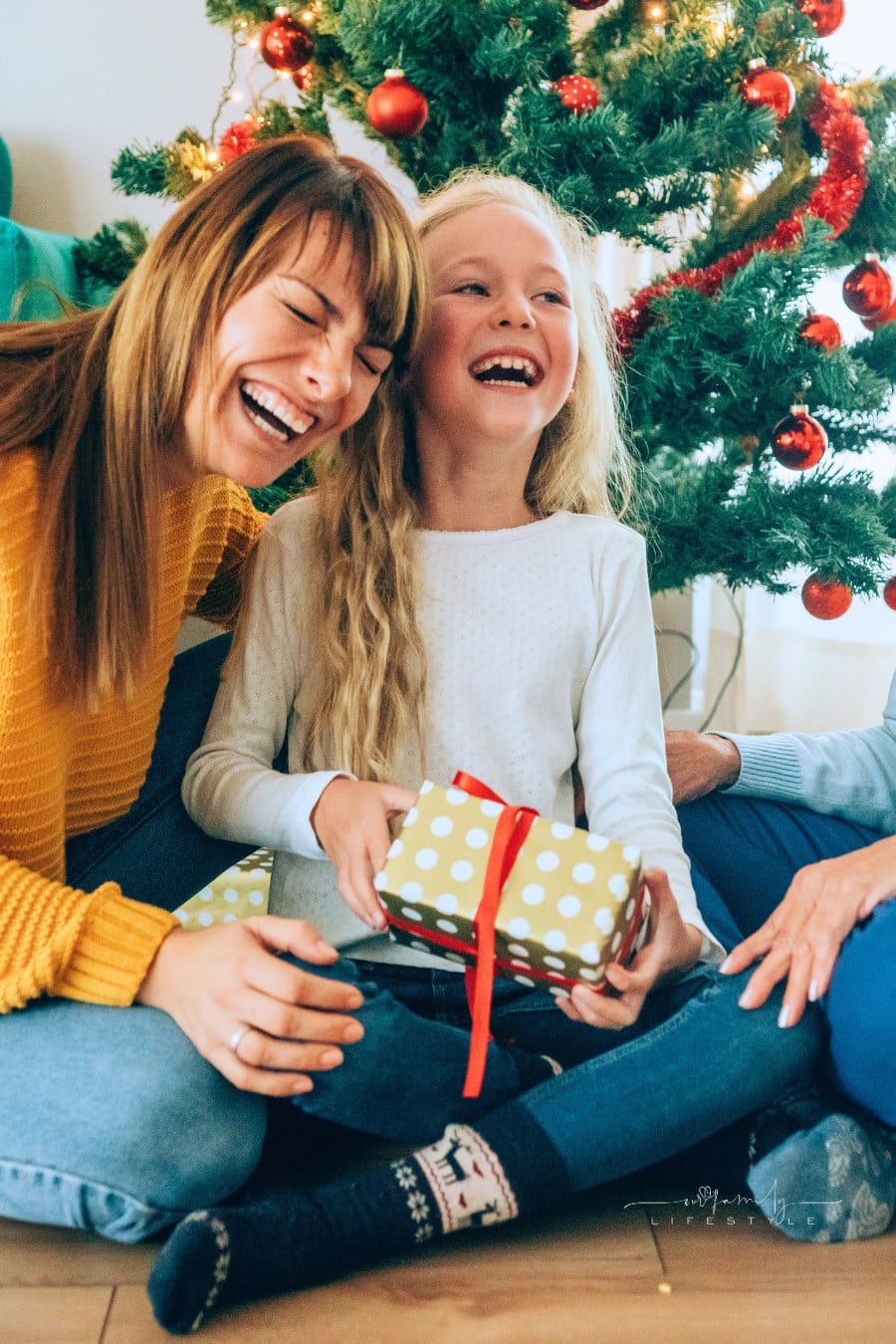 Three generation family having fun while opening Christmas gifts by tree