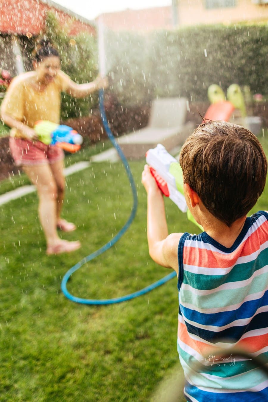 mother and son playing with water guns in the backyard