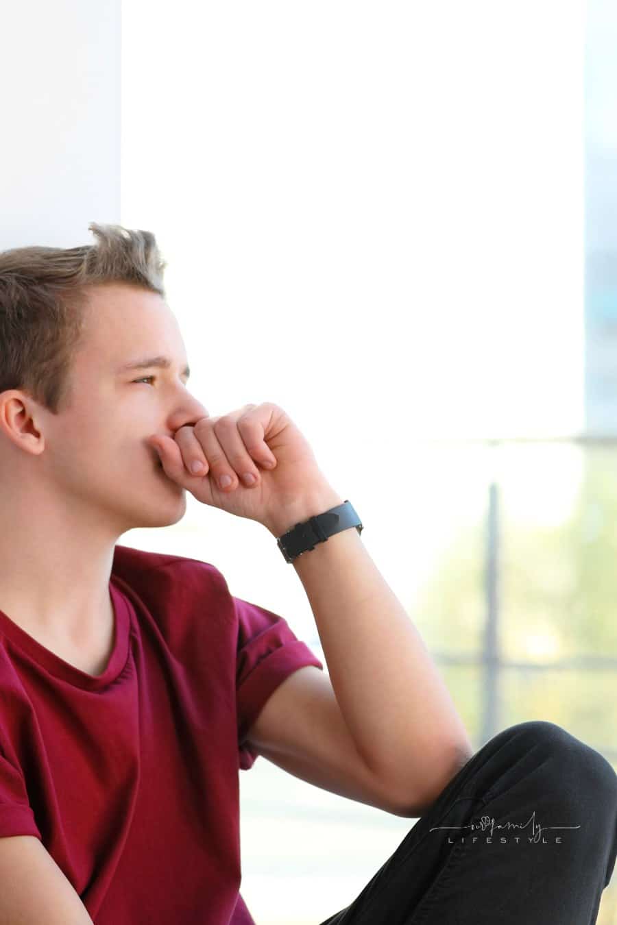 Upset Teenage Boy Sitting Alone near Window Indoors