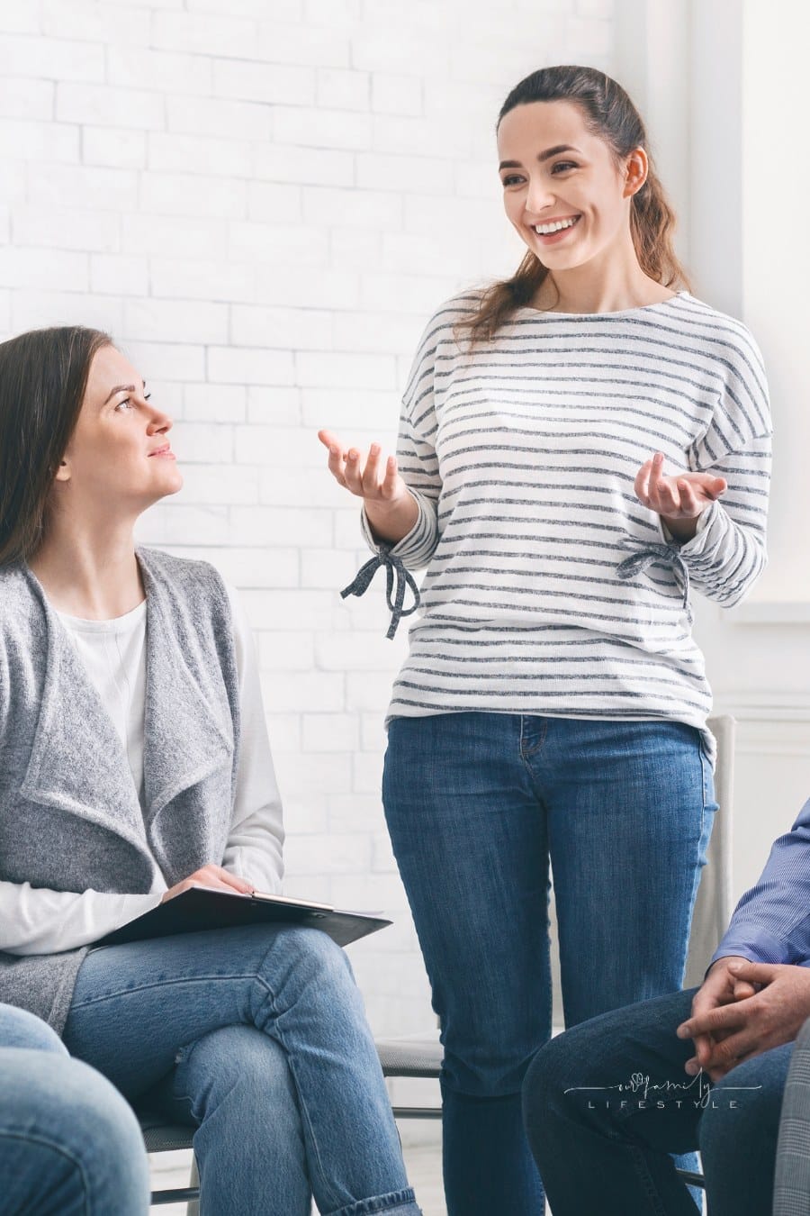 Joyful woman sharing her progress success with group on therapy session in rehab