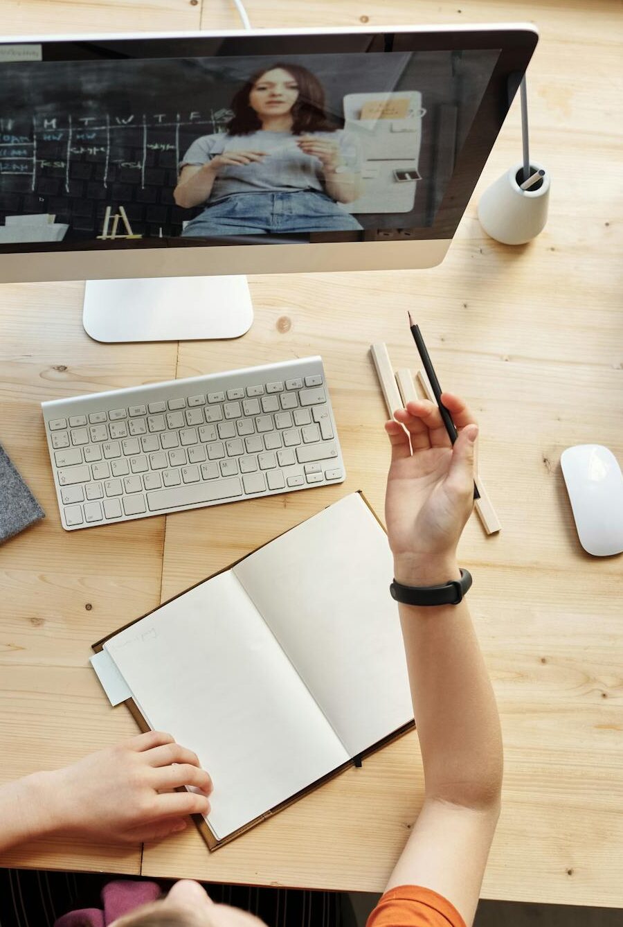 Teen girl actively learning in an organized home workspace via online class on a desktop computer.