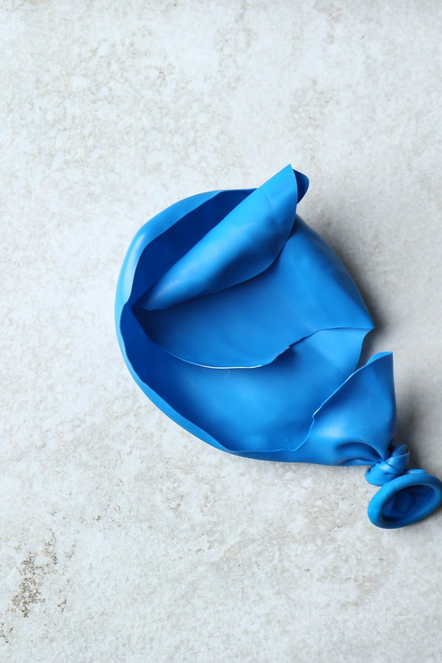 busted, popped blue balloon on granite cuntertop