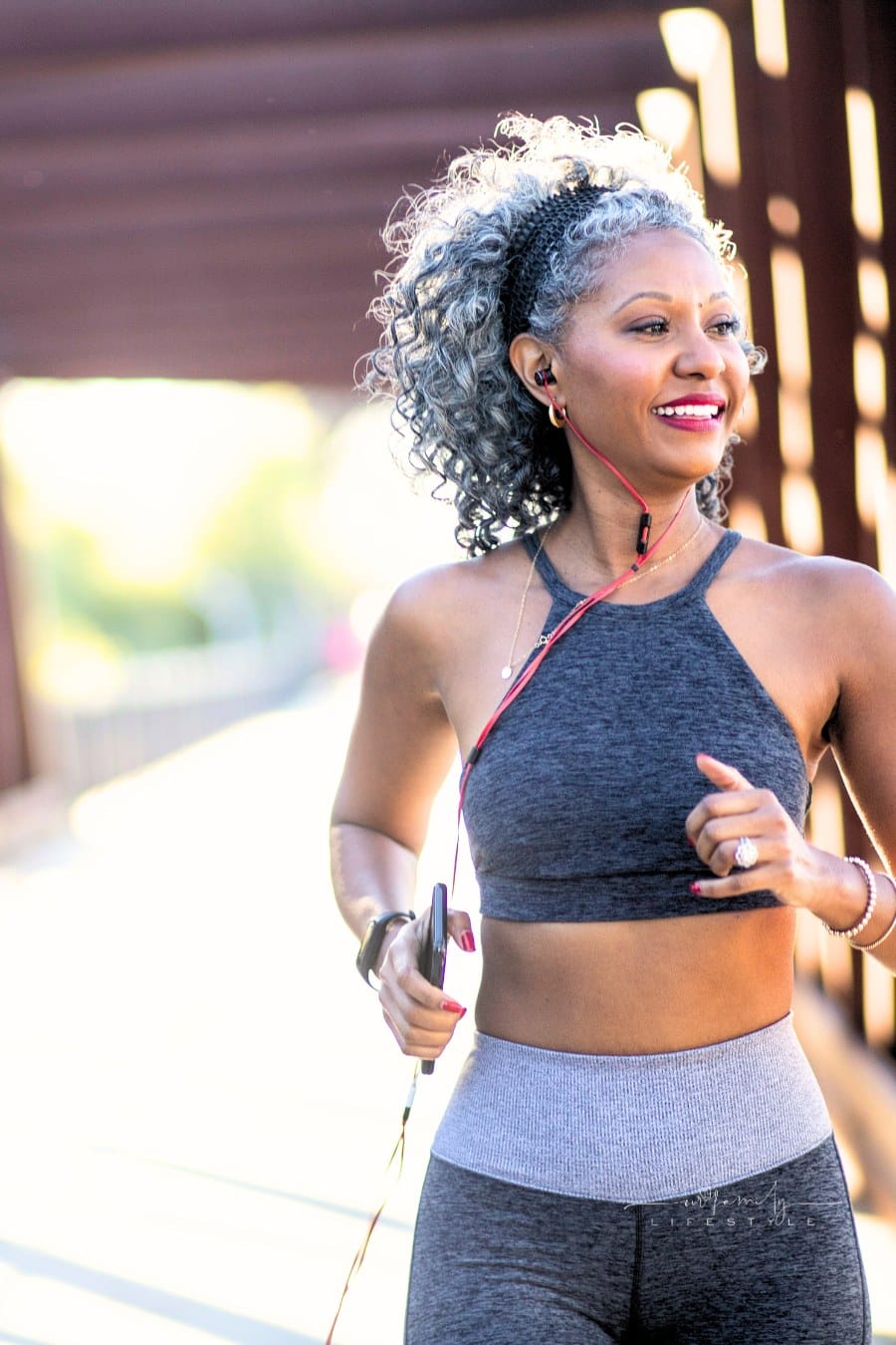 middle aged Black Woman Running on a bridge with headphones in