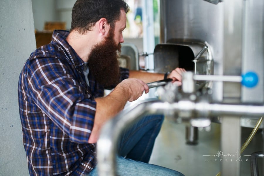 Brewery Worker Cleaning Out Hop Mash from Fermenting Tank