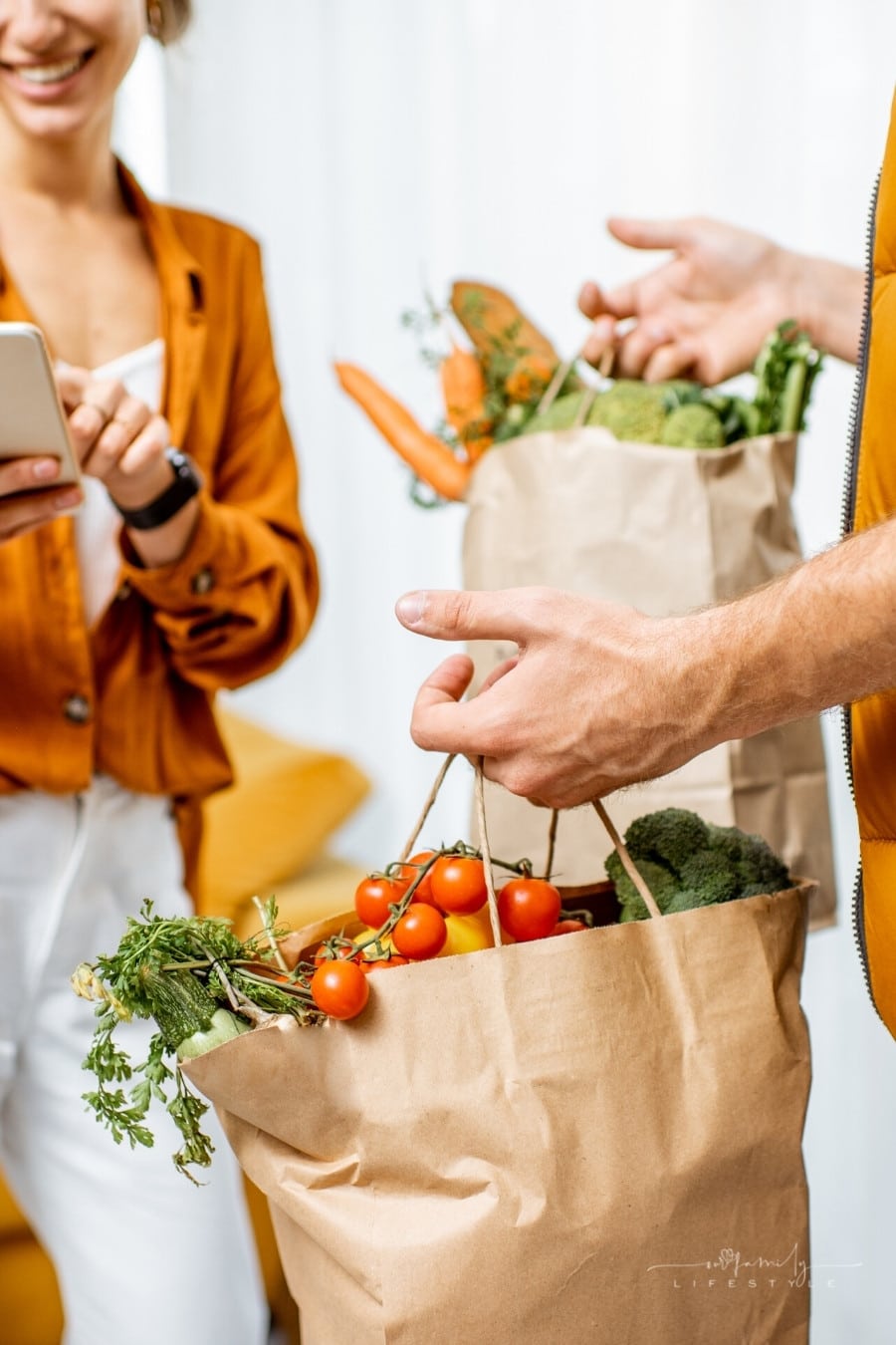 woman with smartphone checking food delivery bags