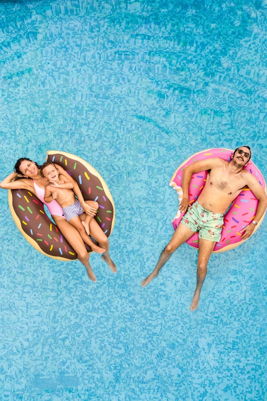 Family relaxing in swimming pool on donut shaped floats