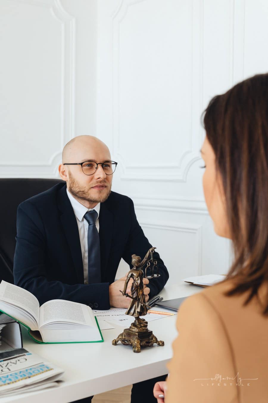 male attorney sitting behind desk talking to female client