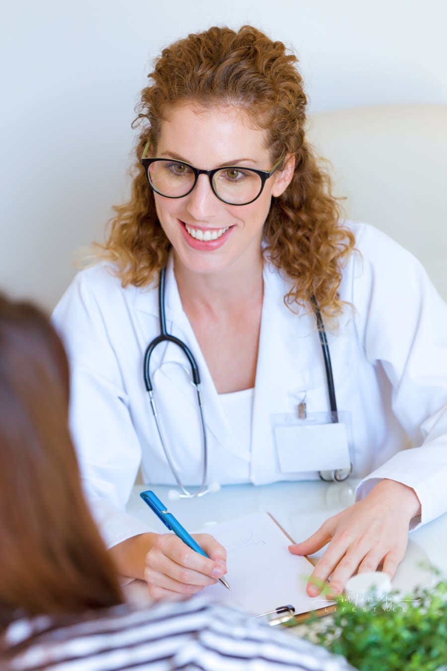 Female Doctor Prescribing Medication for Patient in the Office.