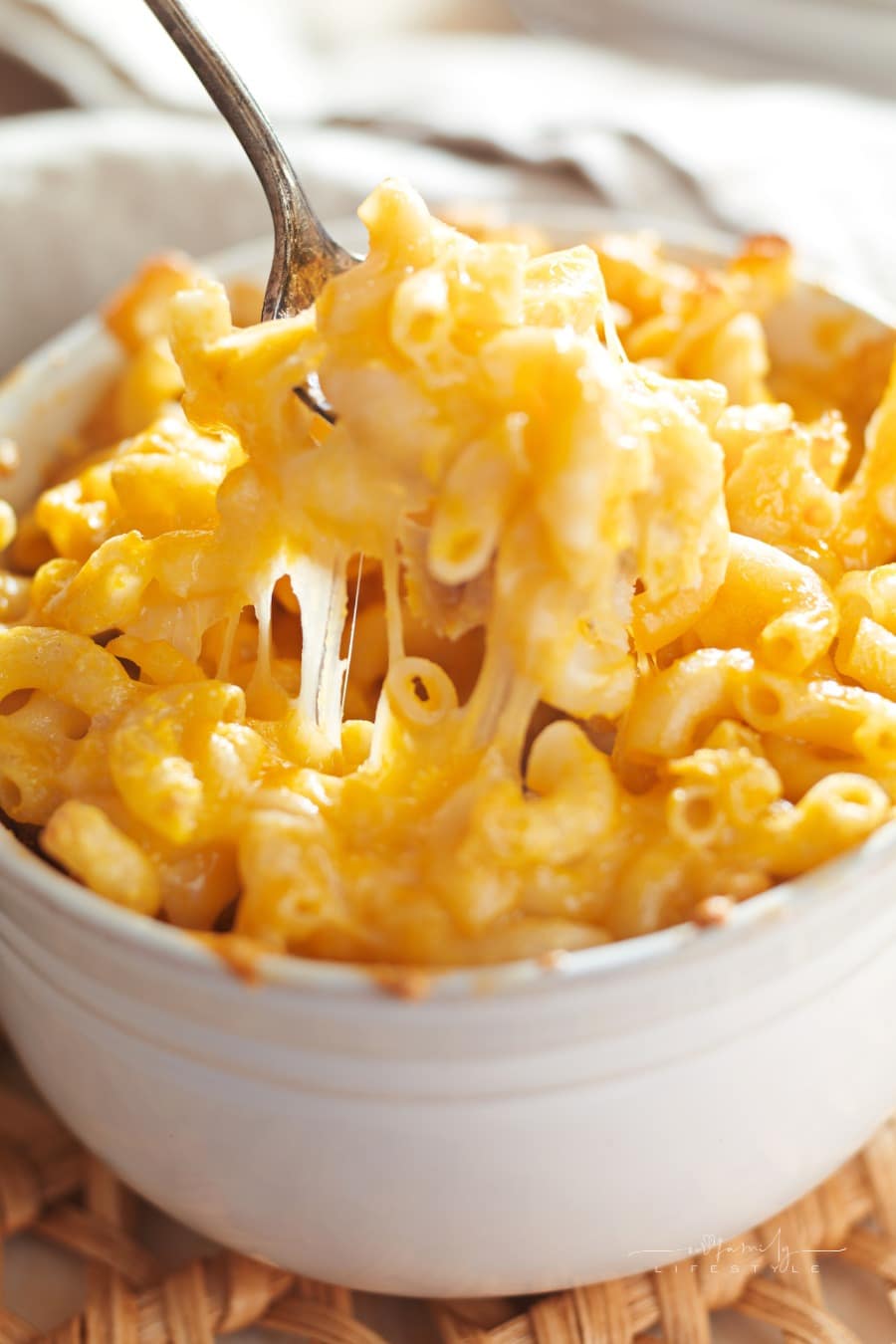 spoom picking up a bite of extra cheesy and creamy mac and cheese from a bowl