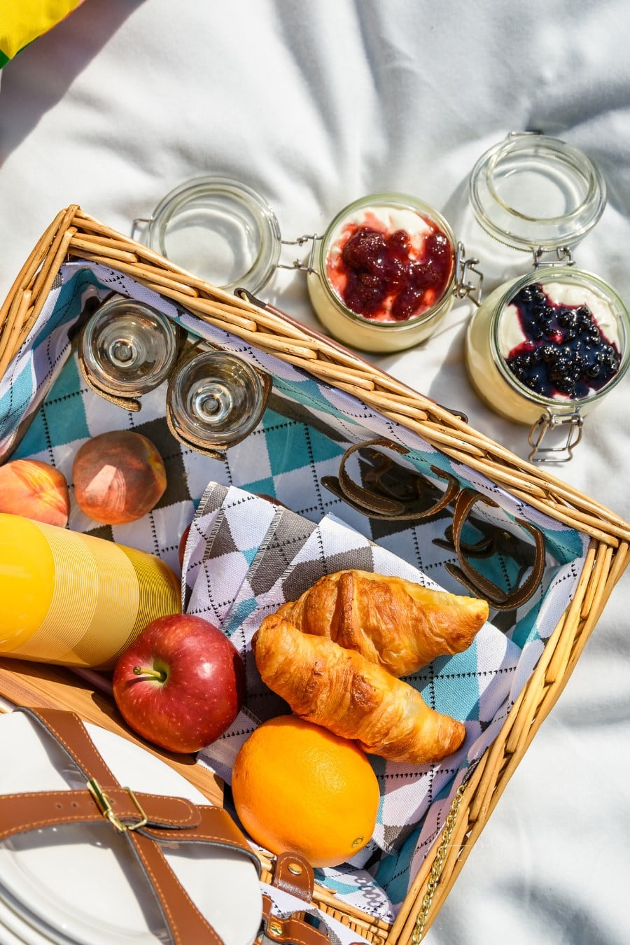Picnic basket with fruits, orange juice, croissants, quesadilla and no bake blueberry and strawberry jam cheesecake