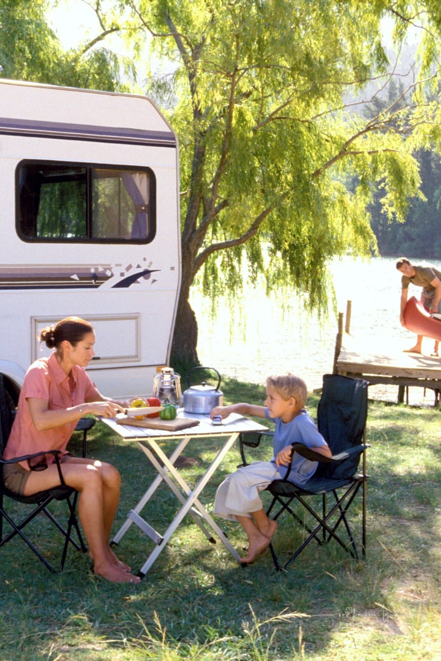 mom and son cutting vegetables at outdoor table while RV camping