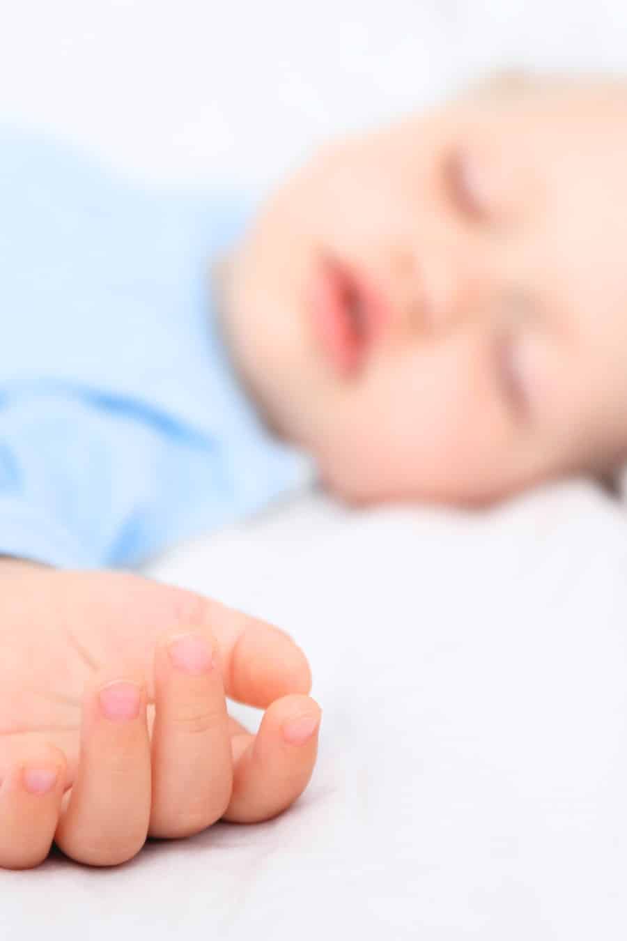 Baby boy sleeping on sed in blue pajamas