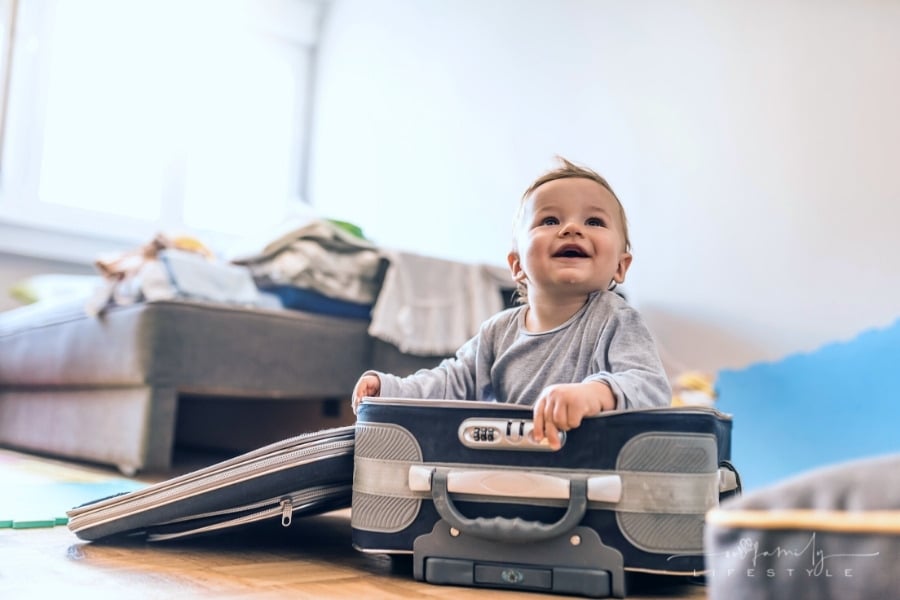baby sitting in an open suitcase smiling