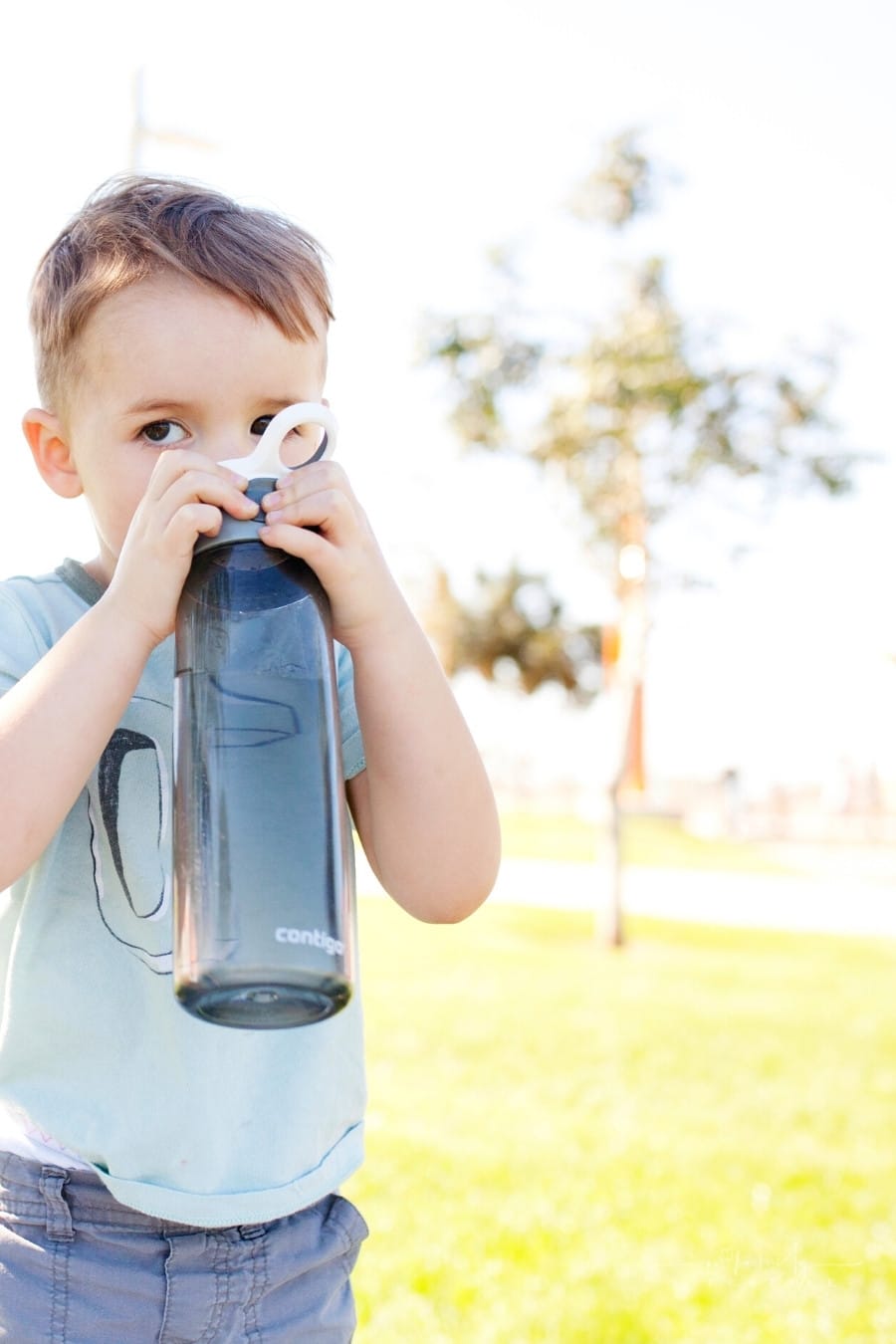 little boy drinking from a reusable water bottle