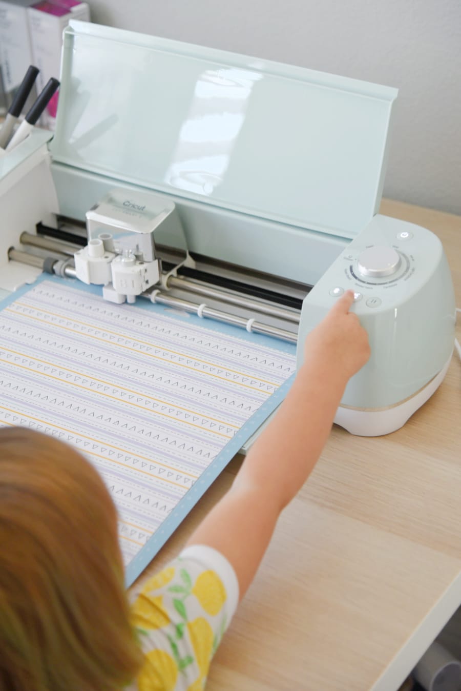 toddler helping push GO button on Cricut Explore Air 2