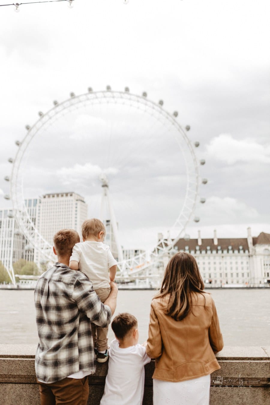 family standing across Thames from London Eye