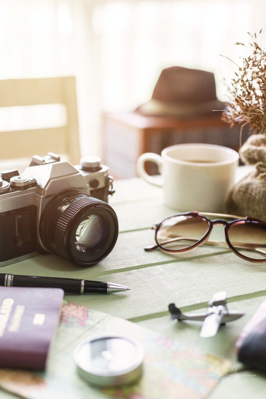 camera with pen, passport, map and travel items on table