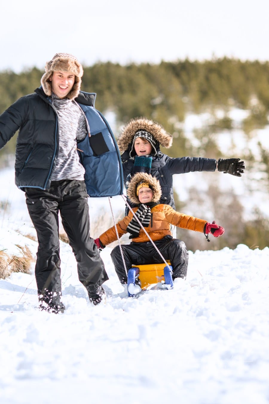 Father and sons having winter fun sliding on show