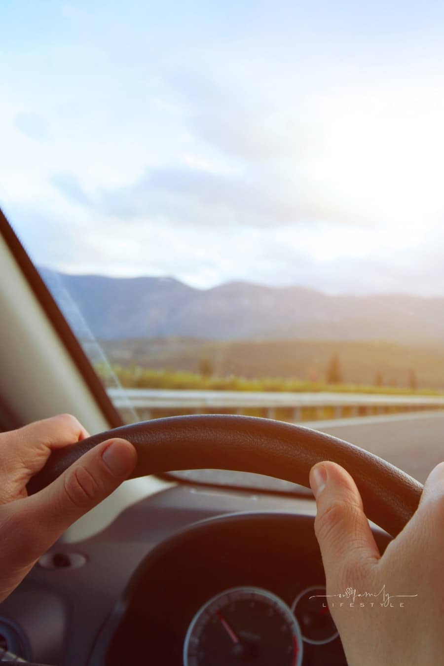 Hands of a driver on steering wheel of a car and empty asphalt road