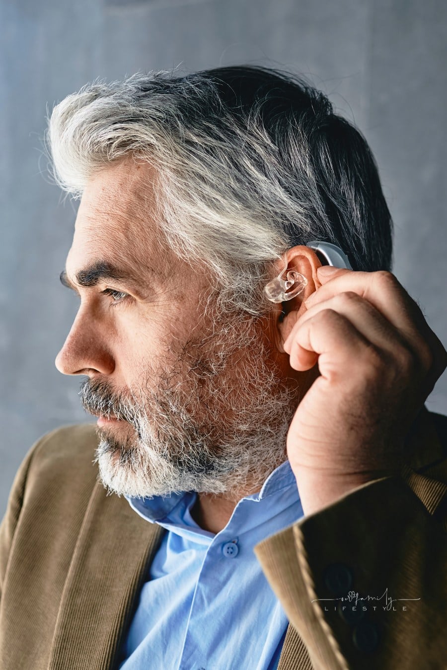 man in suit putting on a hearing aid