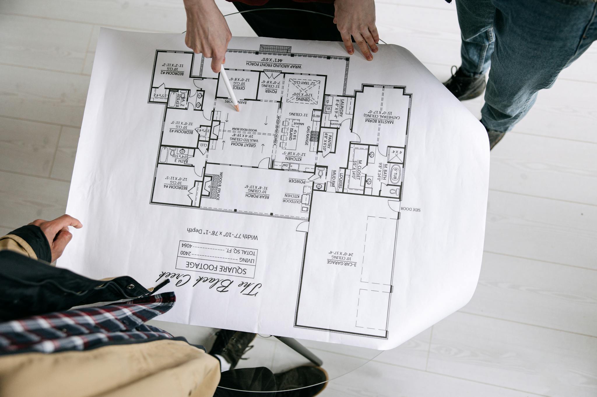 Two architects examining a detailed floor plan blueprint on a table indoors.
