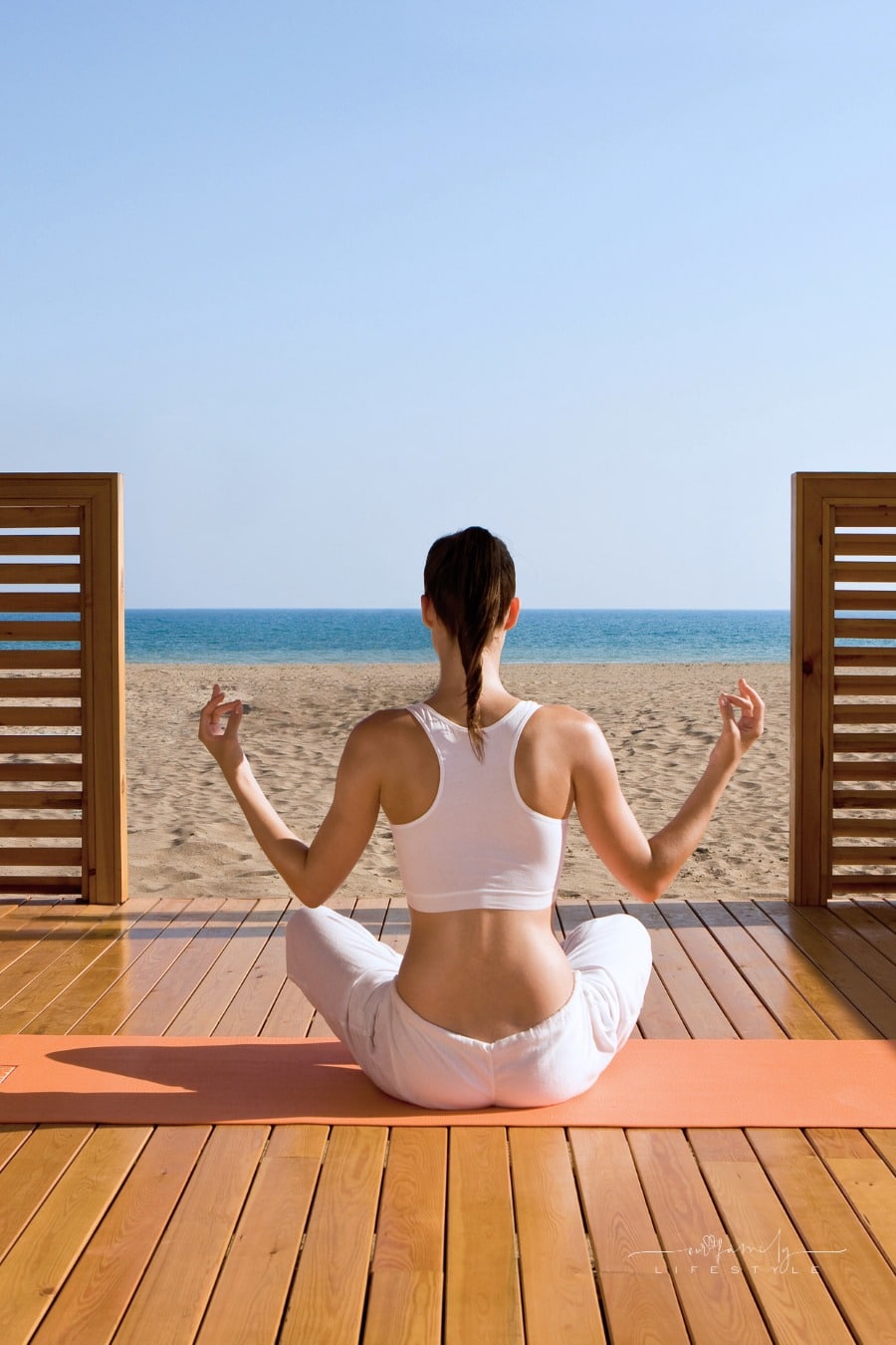 woman meditating on wooden deck in front of ocean