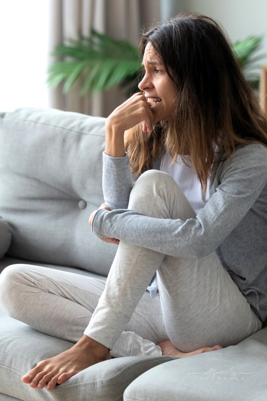 depressed woman on couch chewing on her fingernails