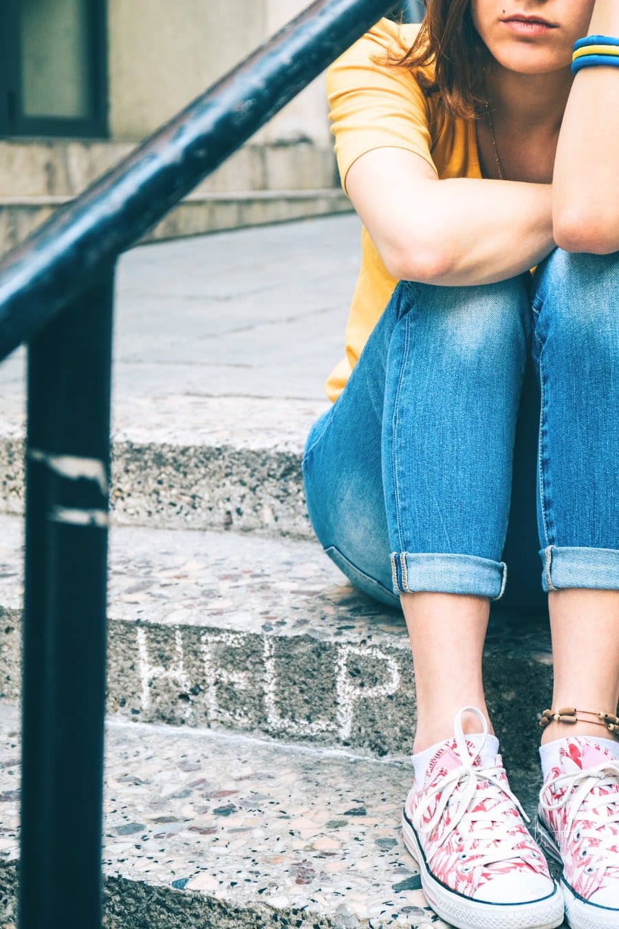 depressed female sitting on stairs and holding head with her hands