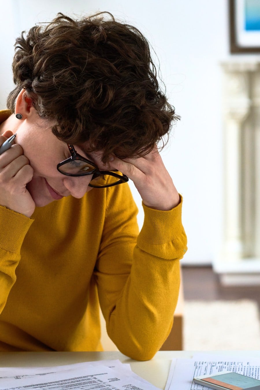 Close-up of busy woman sitting at wooden coffee table and calculating tax figures while examining tax returns papers