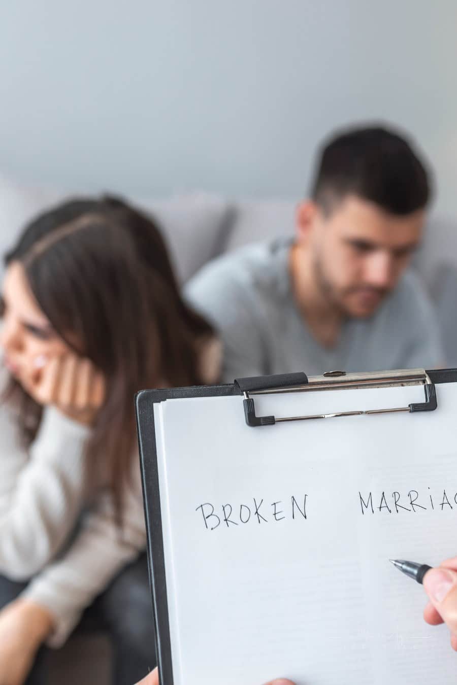 Sad marriage talking with female therapist, horizontal. Married couple during psychotherapy and psychologist back view. Young marriage in crisis trying solve problem during psychotherapy