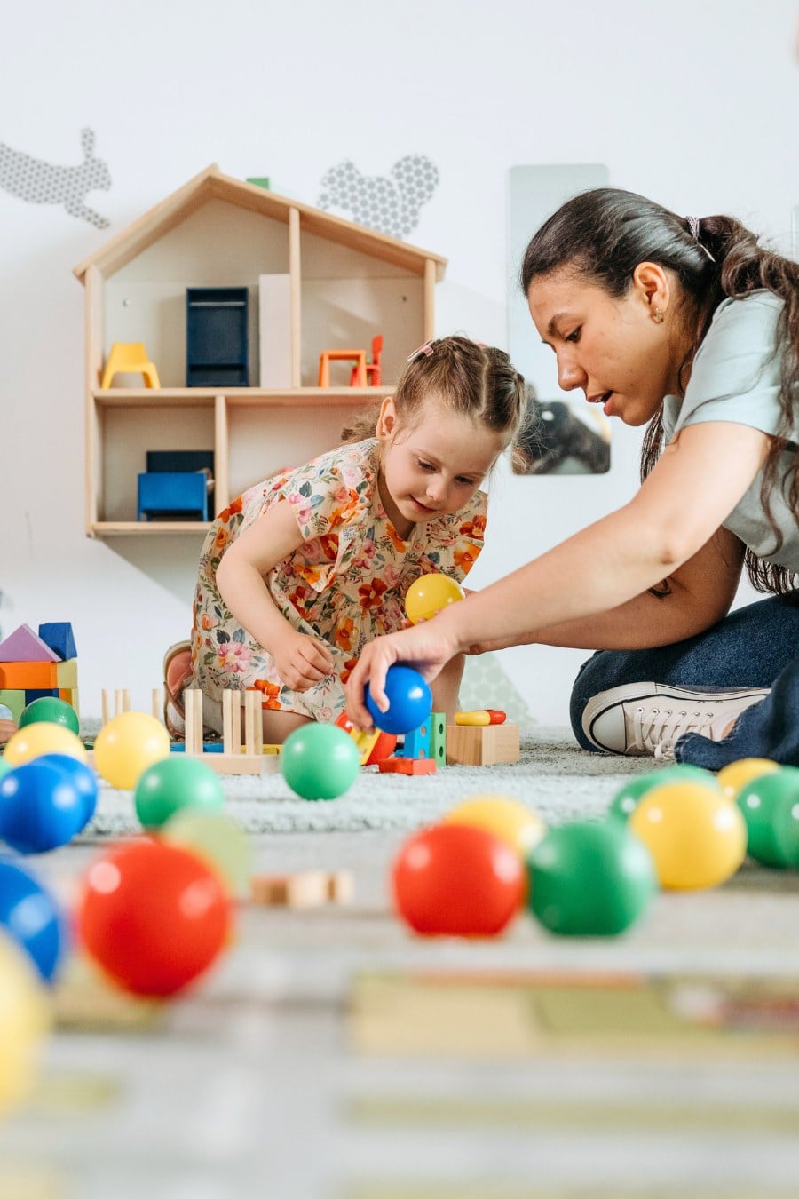 A Woman Sitting on the Floor playing with a toddler