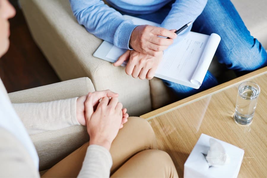 Middle-aged psychologist sitting next to his patient and listening to her childhood story in order to find reason of her dise