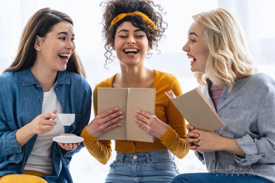 three women laughing together over a book