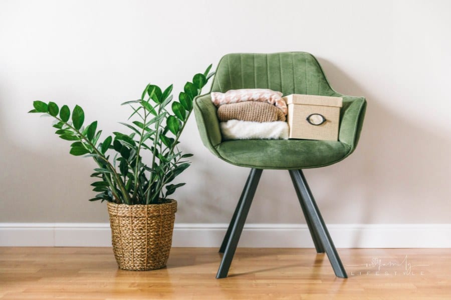 Stack of clothes on a green chair in a light room. Home space organization, spring cleaning and decluttering
