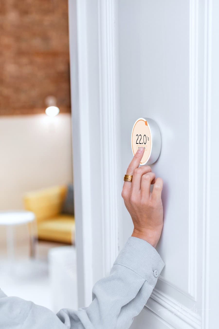 woman adjusting programmable thermostat in home