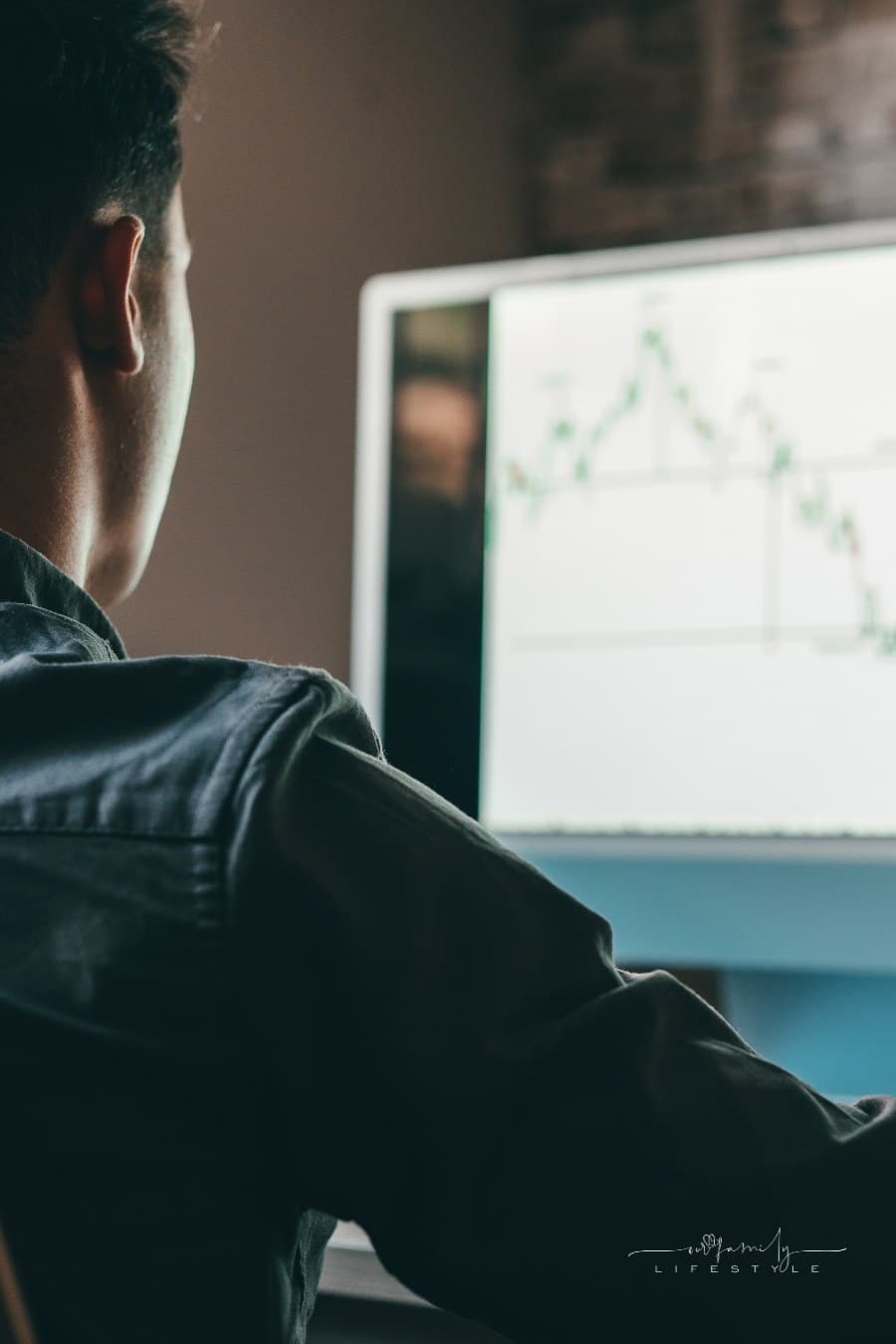 young day trader analyst looking at financial stock market charts rate dynamic, trading data indexes growth using mobile phone and laptop for digital analytics.