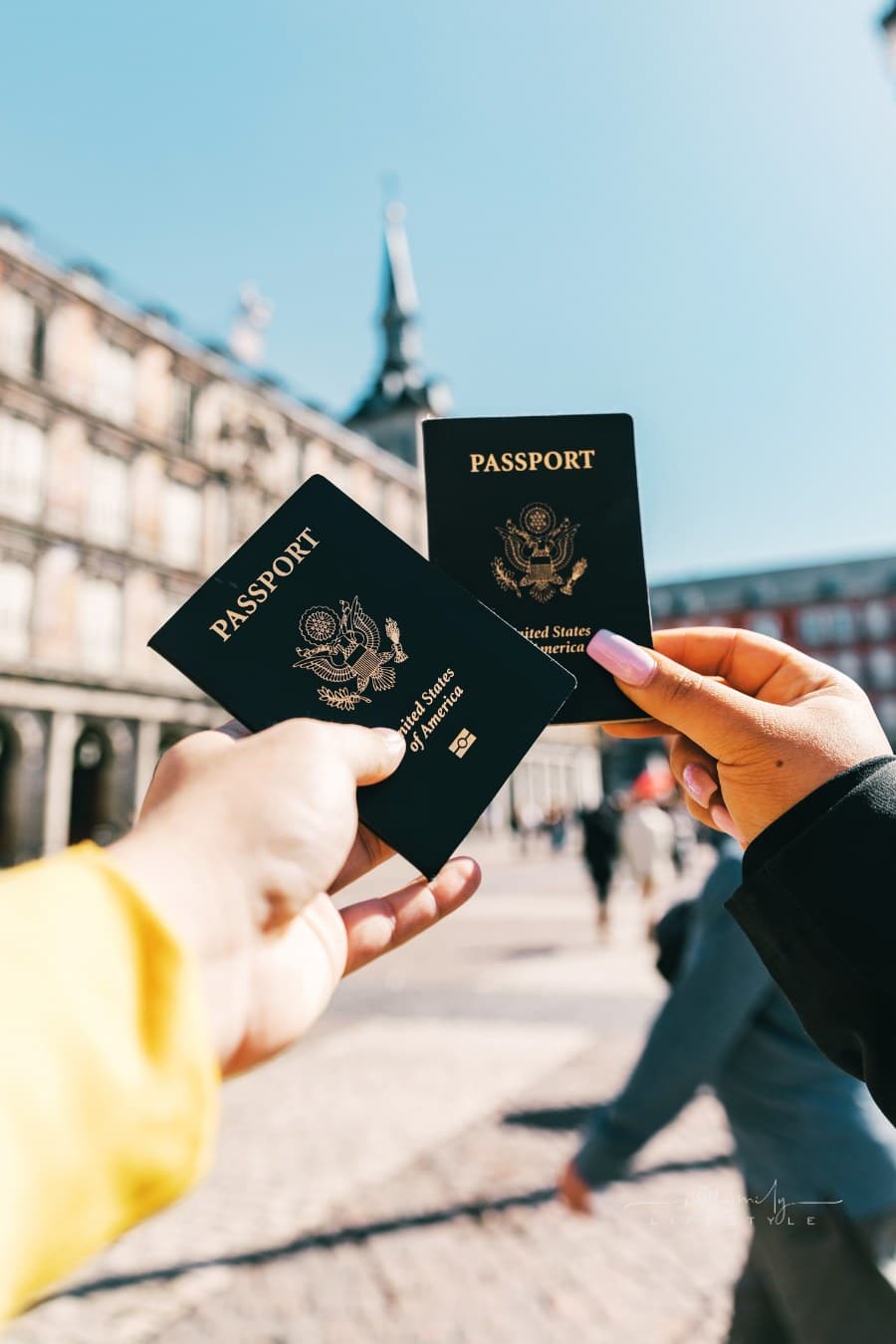 tourists holding US passports on European street on sunny day