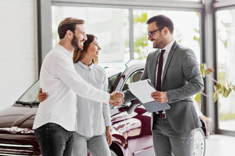 Young couple buying a car at auto dealership