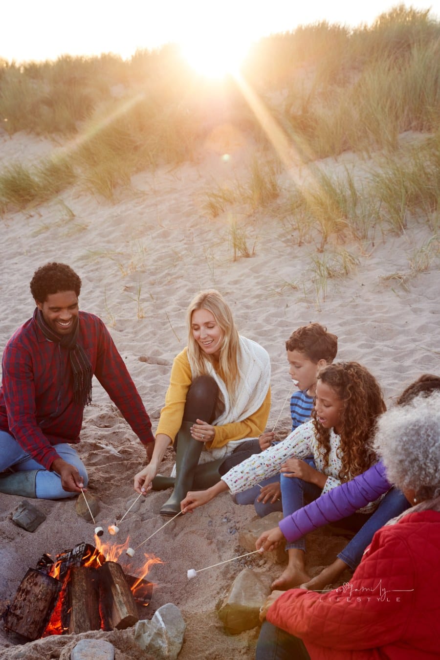 Multi-Generation Family Toasting Marshmallows around Fire on Winter beach vacation