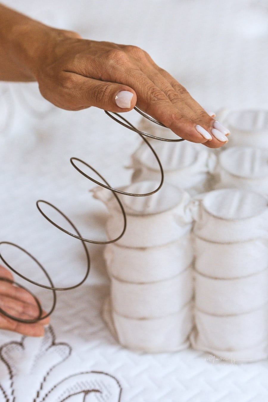 Mattress spring in the hands of a woman. Pocket independent spring. The concept of filling a mattress.