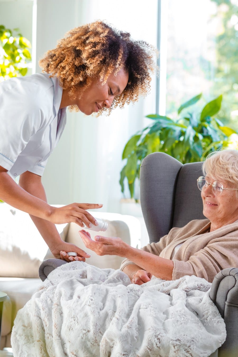 Home carer giving medicine to senior patient