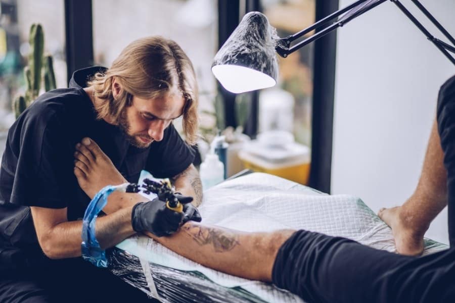 tattoo artist in studio tattooing another man's leg