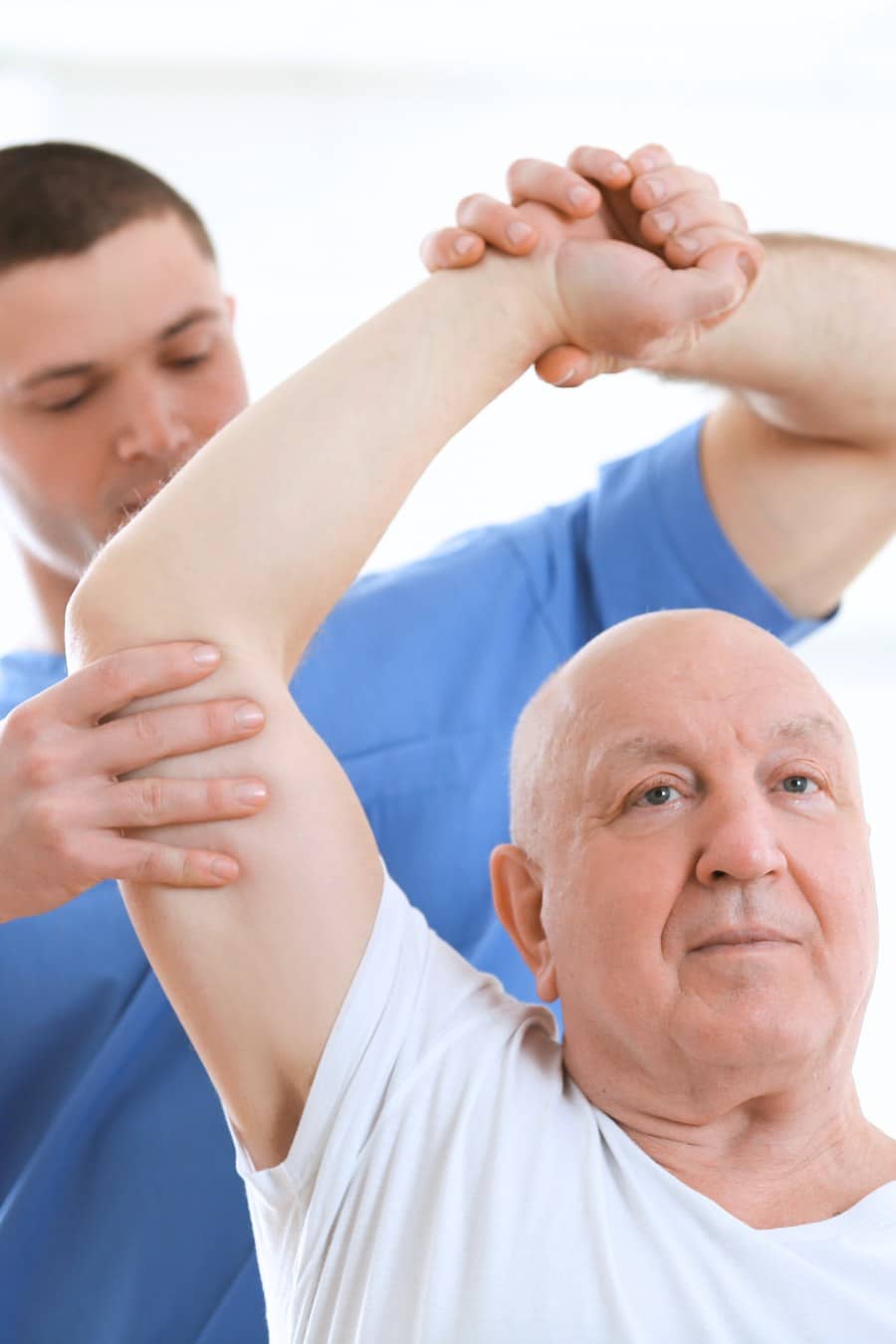 Physical therapist Lifting Arm of Elderly man