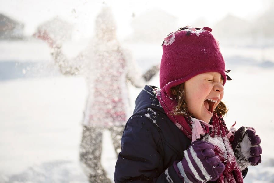 Happy kids playing in sno having a snowball fight