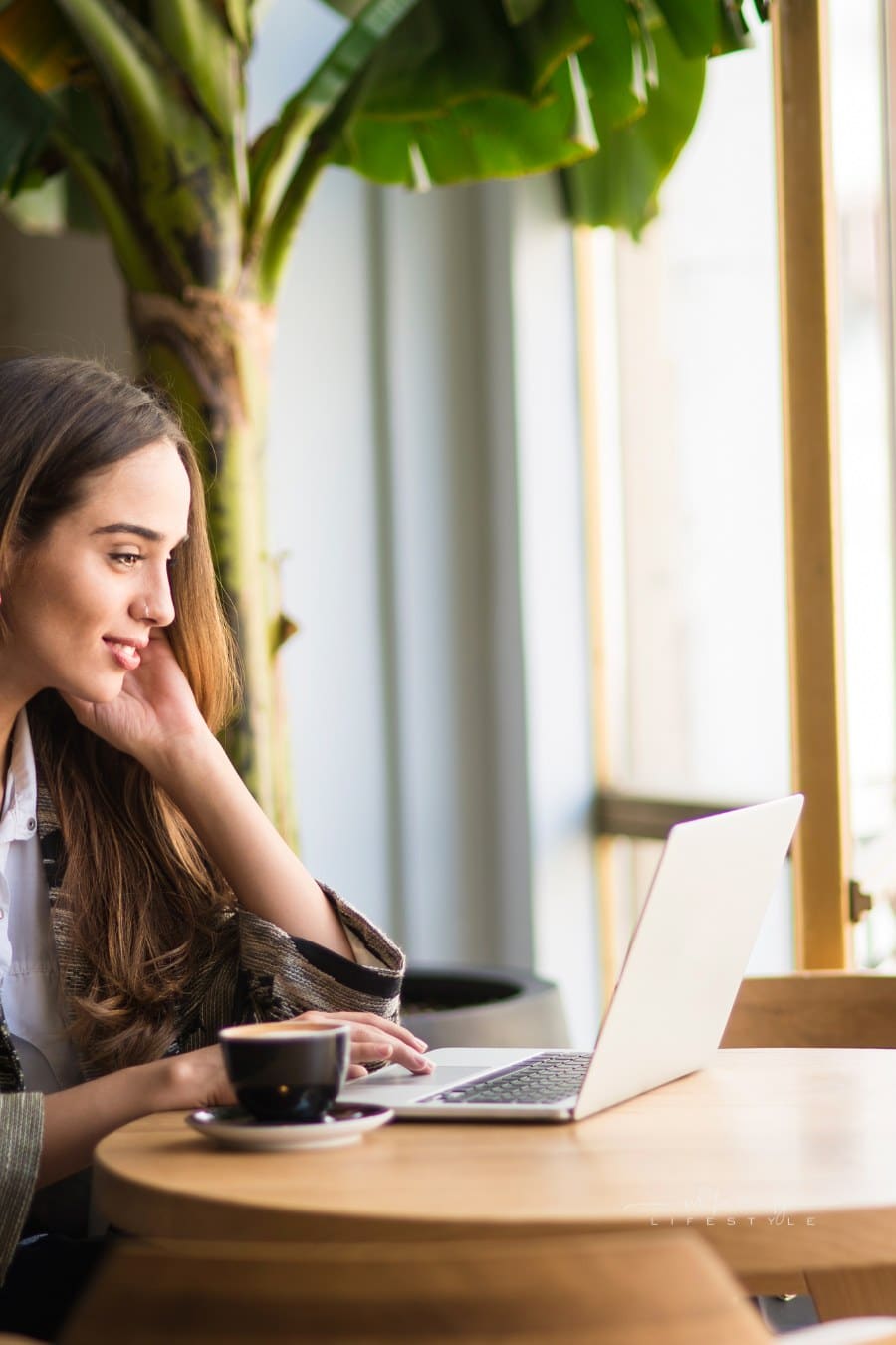 smiling woman using laptop in cafe