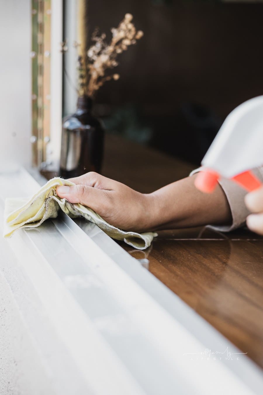 House Cleaner Spraying and Wiping Windowsill