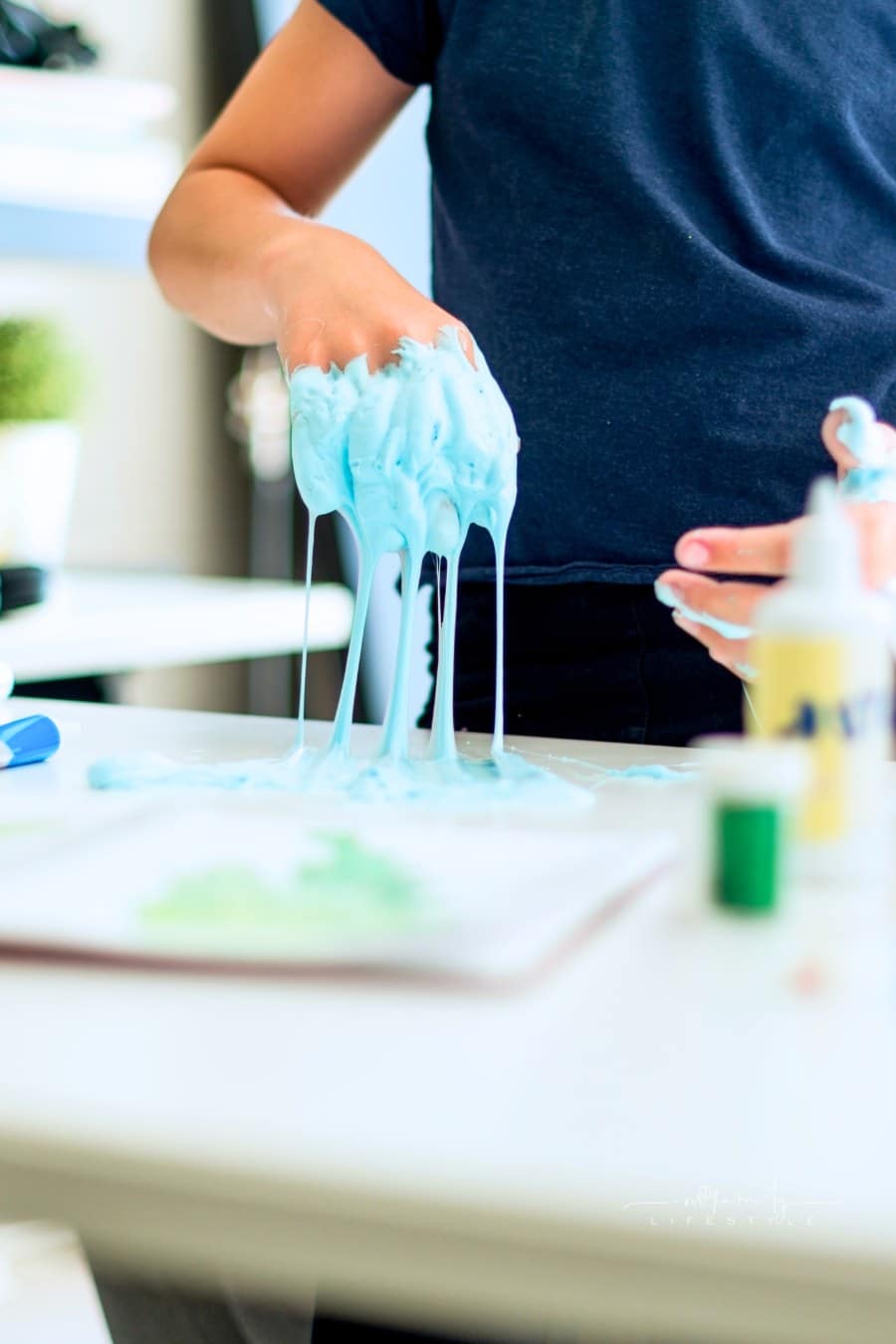 child's hands playing with blue slime