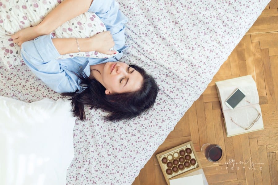 young woman laying on her bead holding a pillow while feeling depressed